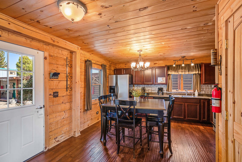 Full kitchen and dining area in the Cowboy Cabin at the Bucking Moose, with wood cabinets and a high-top table for four.