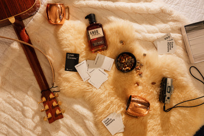 Still life of Cards Against Humanity with drinks and snacks on a bed at the Bucking Moose in West Yellowstone, Montana
